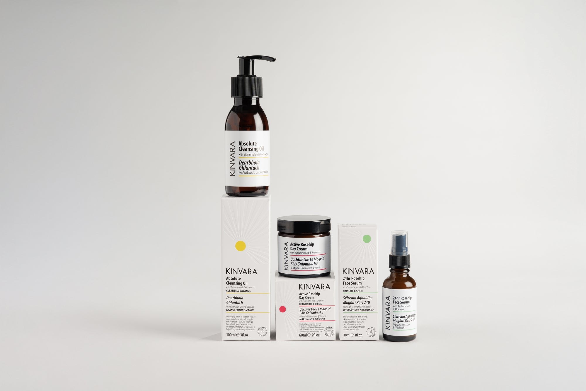The Kinvara range photographed together, the cleansing oil, cartons and bottles on a pale grey surface